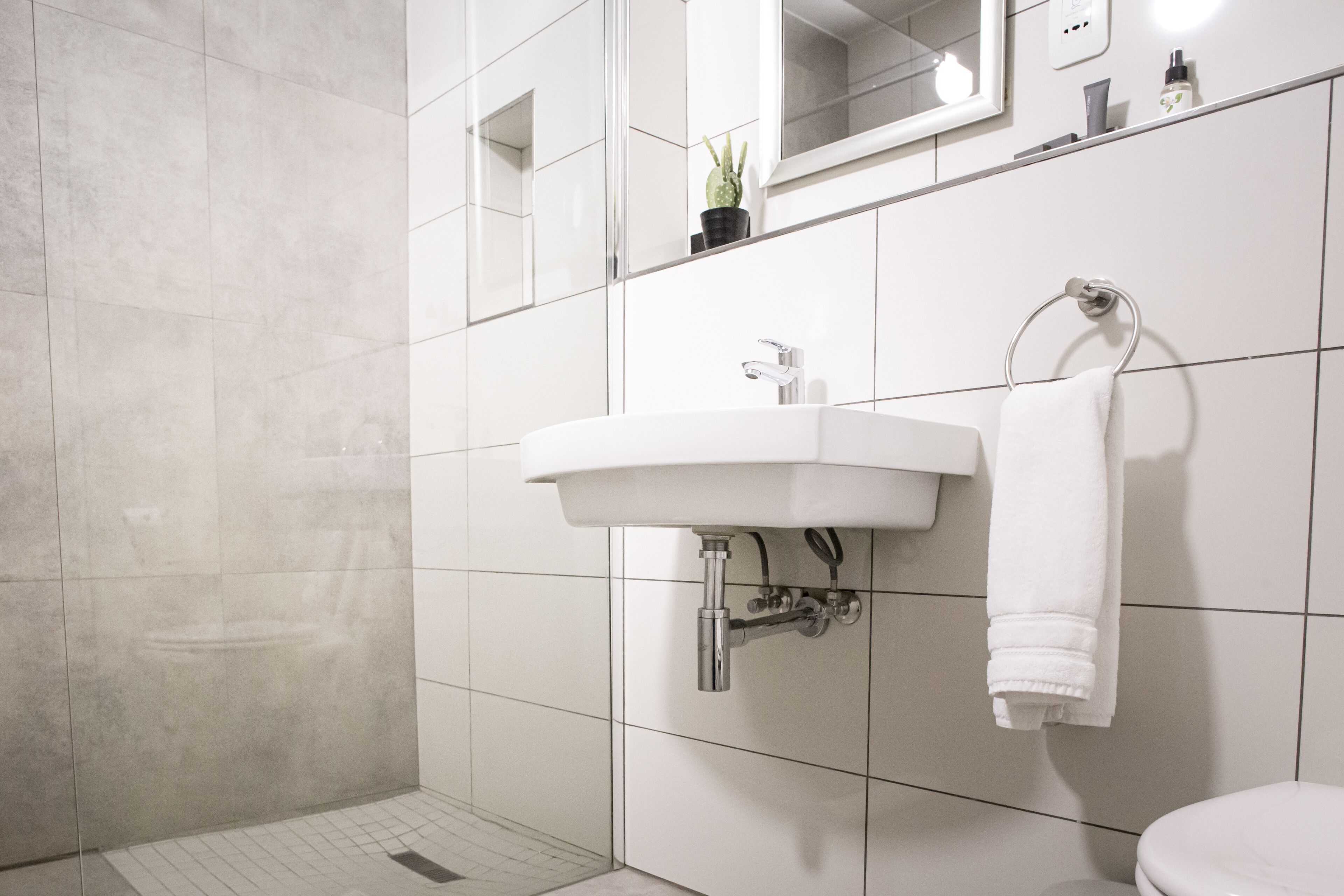 A modern bathroom with a white sink, a towel rack, and a mirror above the sink.