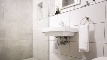 A modern bathroom with a white sink, a towel rack, and a mirror above the sink.