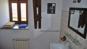 Une salle de bain avec une fenêtre, un radiateur, un lavabo et un miroir.