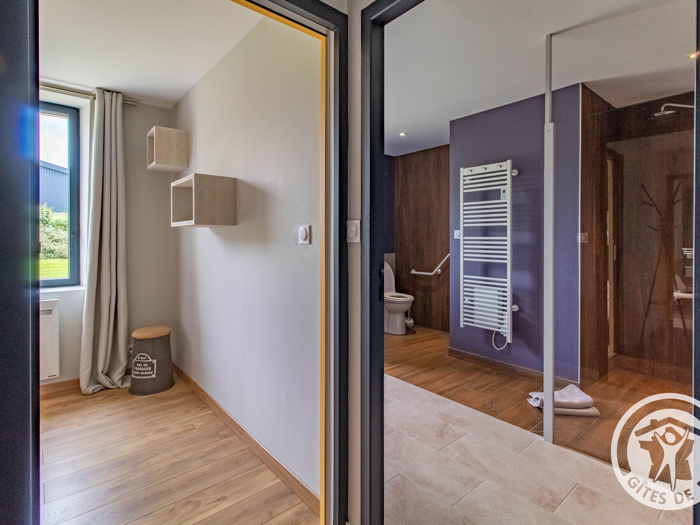 Een moderne badkamer met douche, toilet en een handdoekhouder.
