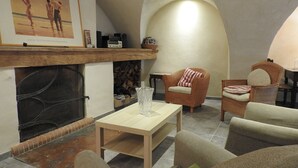 A cozy living room with a fireplace, wicker furniture, and a framed artwork on the wall. - 200 m FROM SKI SLOPES- HOUSE  FOR 12 PERSONS (Chantemerle)