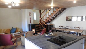 A modern kitchen with a central island, wooden staircase, and a dining area with chairs and a table. - 200 m FROM SKI SLOPES- HOUSE  FOR 12 PERSONS (Chantemerle)