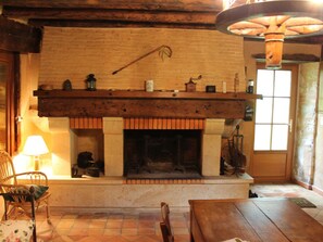 A rustic interior with a fireplace, wooden furniture, and a hanging light fixture.