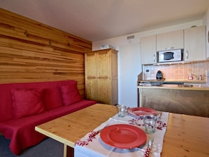A compact kitchen with wooden cabinets, a microwave, and a small dining area with a table set for two.