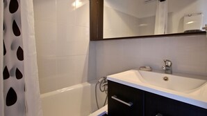 Un baño moderno con bañera, lavamanos y espejo.