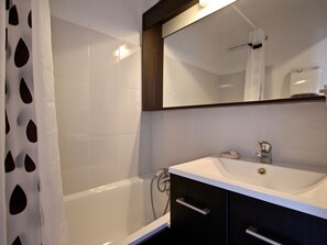 A modern bathroom with a bathtub, a sink, and a mirror.