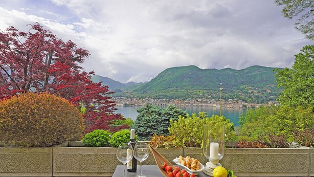 A table with food and drinks, overlooking a scenic view of a lake and mountains.