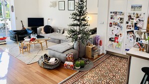A living room with a grey sofa, a coffee table, a small Christmas tree, and a wall with photos and decorations. - Maison de Charme Marseille Borely (Marseille)