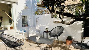 An outdoor patio with metal furniture, a white wall, and a tree providing shade. - Maison de Charme Marseille Borely (Marseille)