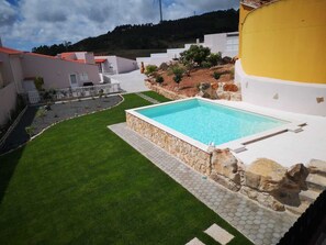 A residential property with a swimming pool, a well-maintained lawn, and a stone pathway leading to the pool.