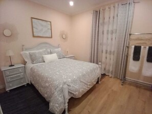 A bedroom with a bed, a bedside table, a lamp, a mirror, and a window with curtains. - Feather House Home (São Bartolomeu de Galegos)