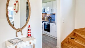 Moderni keittiö, jossa on valkoiset kaapit, sisäänrakennettu uuni ja mikroaaltouuni.