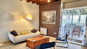 A modern living room with a sofa, coffee table, and two chairs. There is a large window with a view of the outdoors. - Charming Cottage near Loire River with Garden, Covered Terrace & Easy Access to Saumur Attractions (Brain-sur-Allonnes)