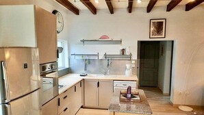 A modern kitchen with a central island, built-in appliances, and a wooden ceiling. - Charming Cottage near Loire River with Garden, Covered Terrace & Easy Access to Saumur Attractions (Brain-sur-Allonnes)