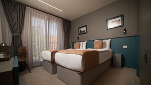 A hotel room with a large bed, two bedside tables, a desk, and a chair. - Hotel Opera (Pristina)