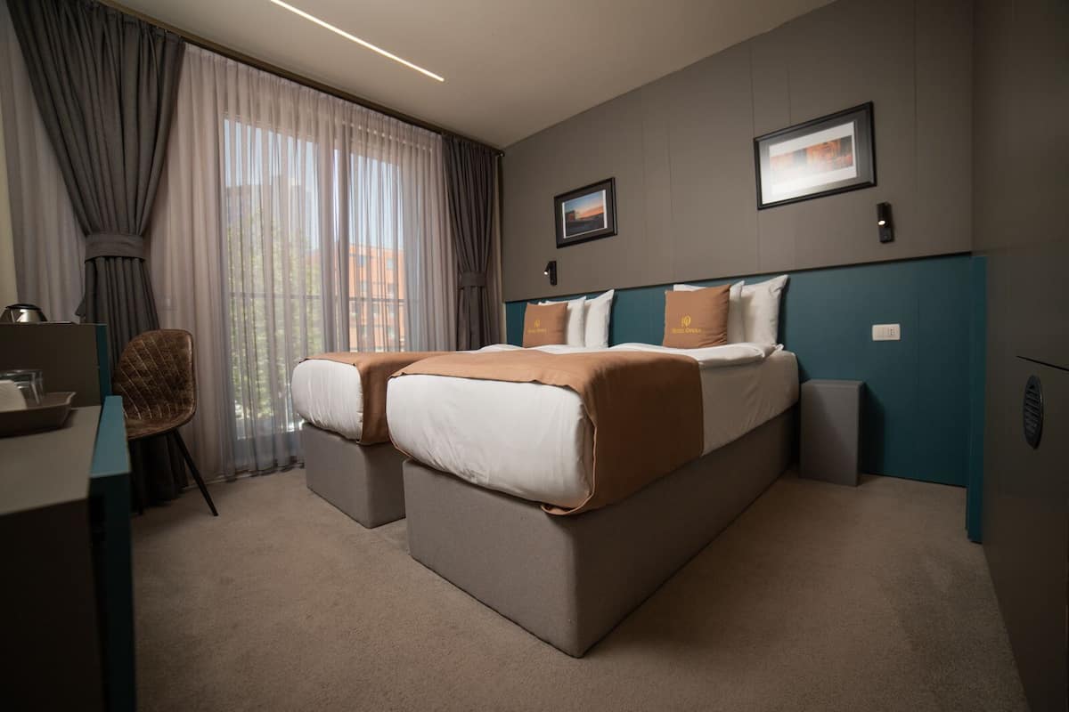 A hotel room with a large bed, two bedside tables, a desk, and a chair.