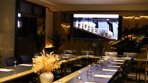 A conference room with a long table, chairs, and a TV screen displaying the word "HOTEL". - Hotel Opera (Pristina)