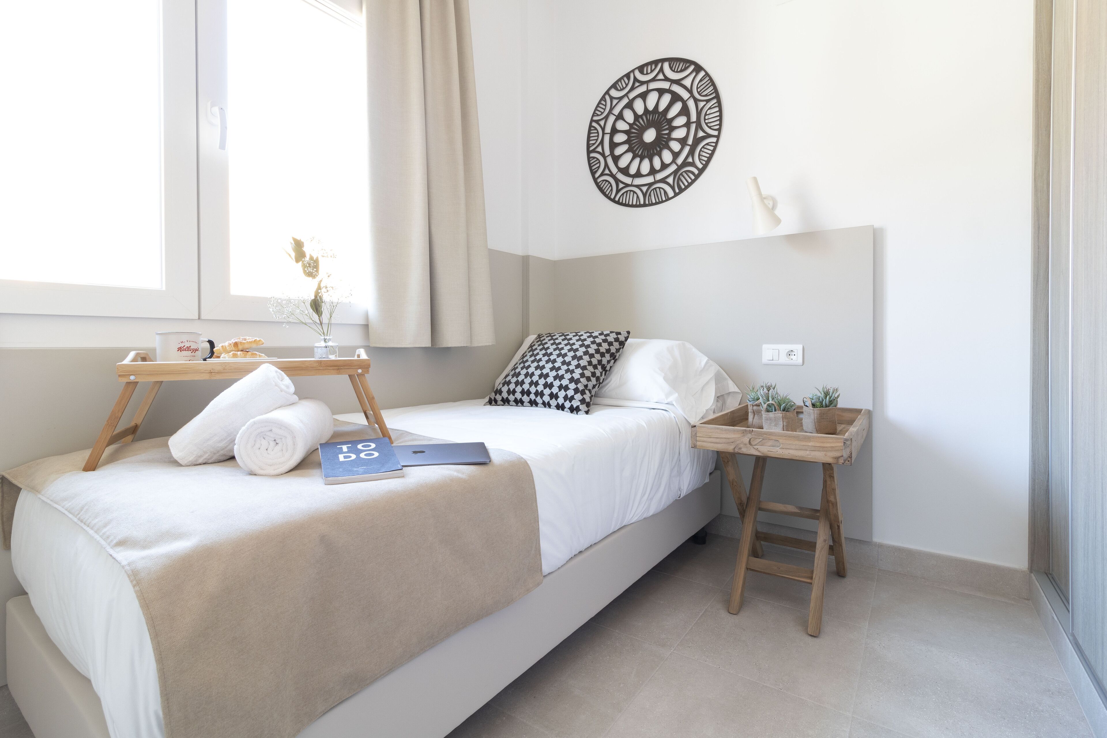 A minimalist bedroom with a bed, bedside tables, and a decorative wall piece.