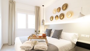 Un lit bien fait, avec un plateau contenant des articles pour le petit-déjeuner, une table de chevet et un mur décoré de chapeaux.