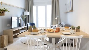 Une salle à manger moderne avec une table en bois mise pour le petit-déjeuner, un téléviseur et un canapé en arrière-plan.