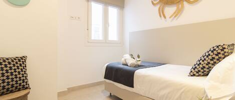 A bedroom with a bed, a wall clock, a window, and a decorative crab wall art piece.