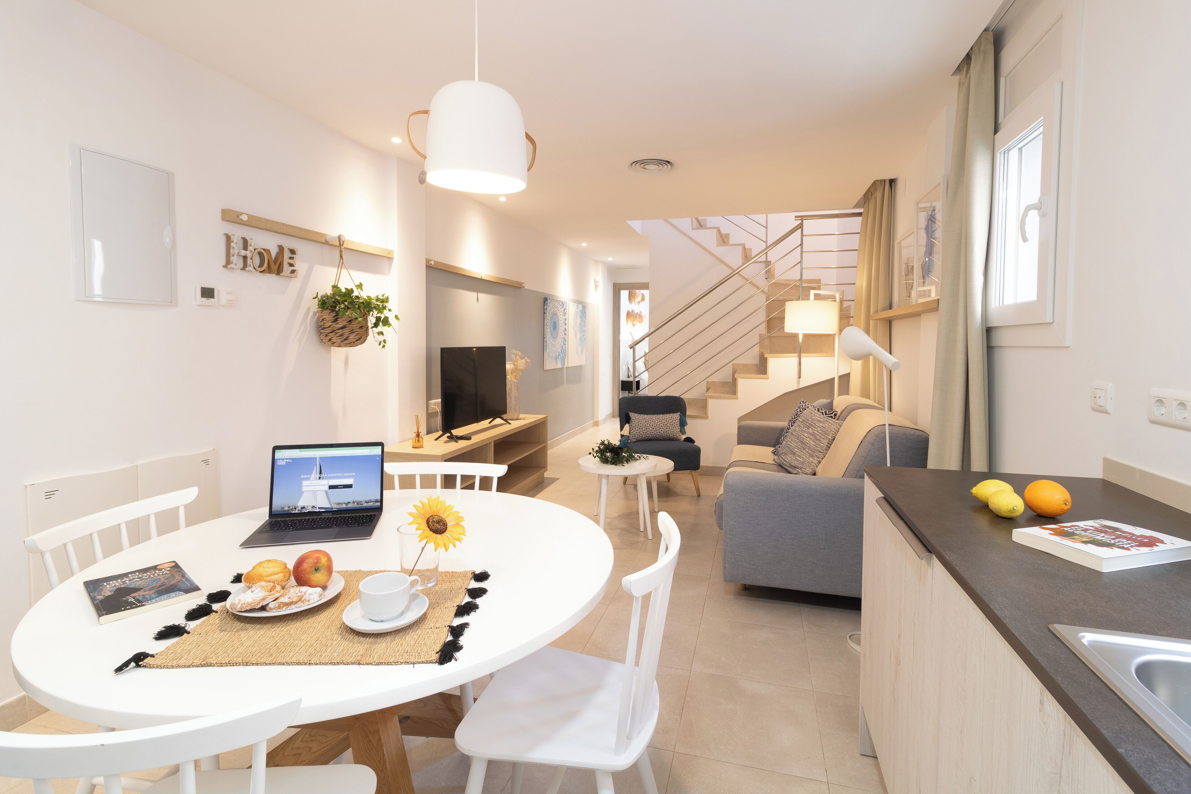A modern kitchen with a dining area, a staircase, and a living room.