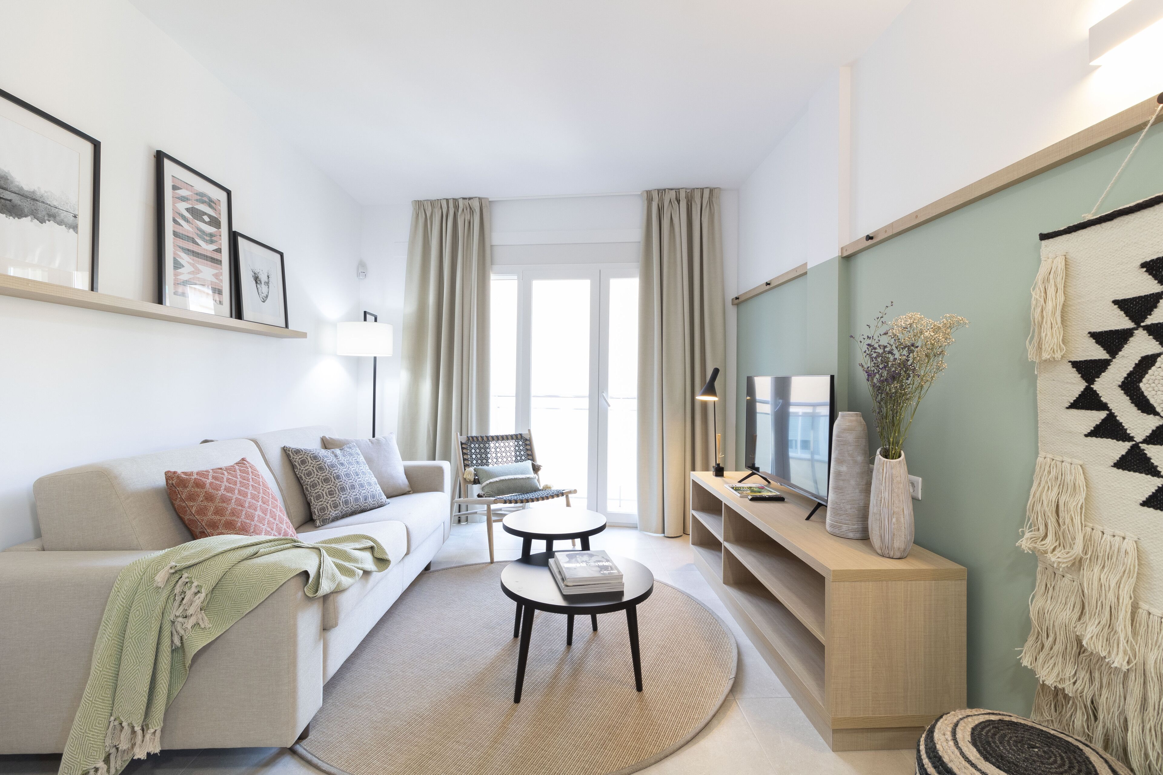 Un salon moderne avec un canapé, une table basse et un téléviseur posé sur un meuble.