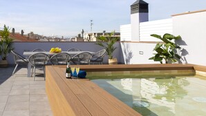 Une terrasse sur le toit avec une piscine, des sièges d’extérieur et des plantes en pot.