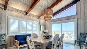 Un comedor con mesa de madera, sillas blancas y sofá azul.