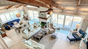 Un salón amplio con techo alto, chimenea y ventana grande con vistas a una terraza.