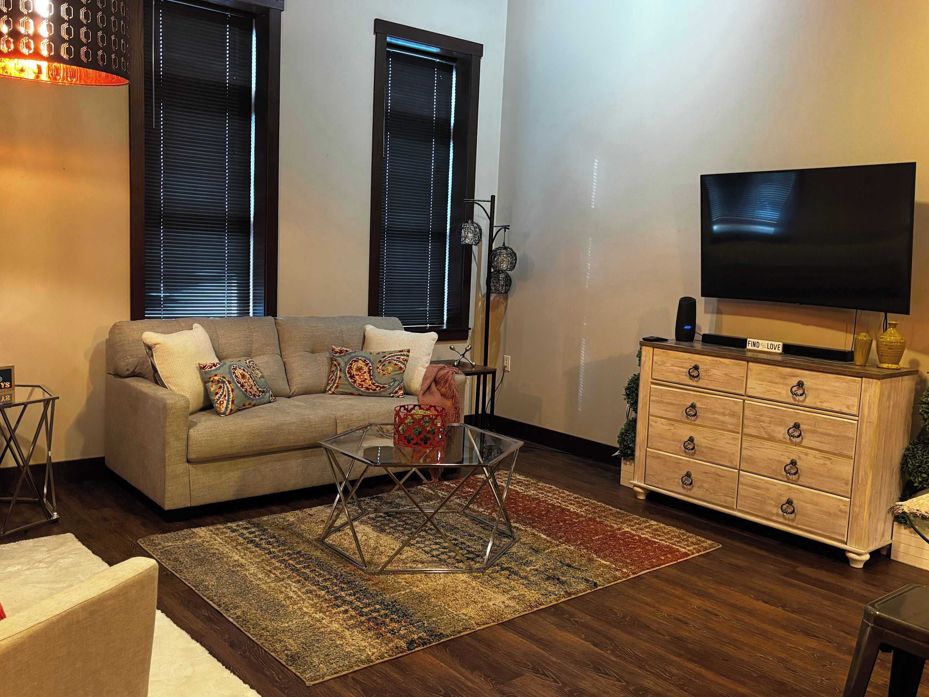 A living room with a sofa, a TV, a wooden cabinet, and a patterned rug.