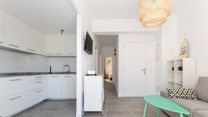 Una cocina moderna con gabinetes blancos, un televisor de pantalla plana y una mesa verde.
