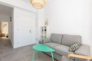 A living room with a grey sofa, a green table, and a white door.