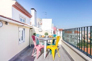 Un balcon avec une table et des chaises, une balustrade et une vue sur les bâtiments.