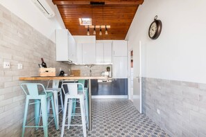 Une cuisine avec des armoires blanches, un plafond en bois et un sol à motifs.
