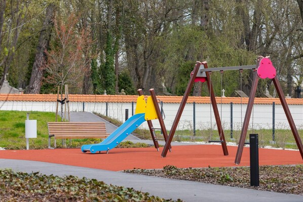 A playground with a slide, swings, and a bench.