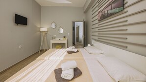 Een hotelkamer met een bed, een bureau, een televisie en een schilderij aan de muur.