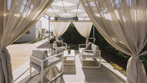 Een terras met witte meubels en dunne gordijnen.