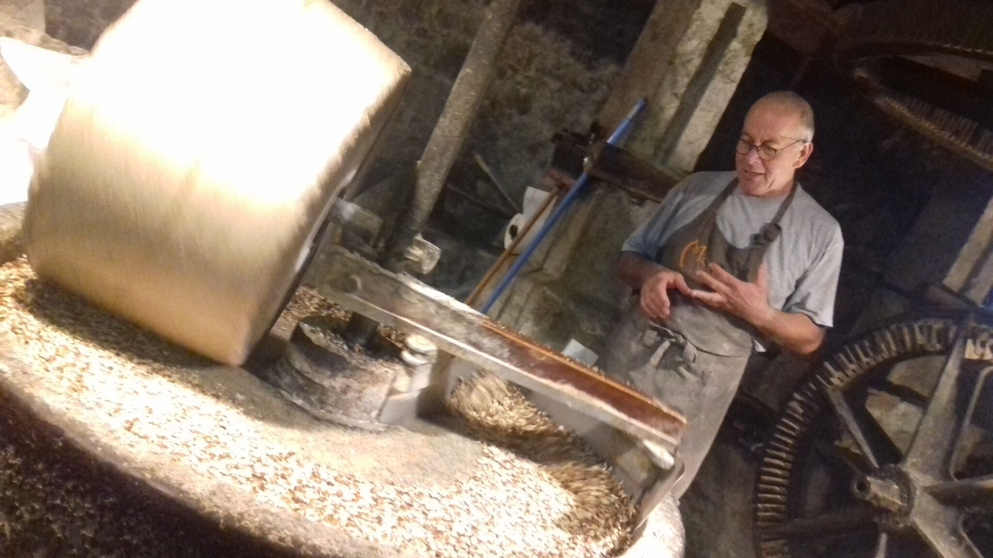 Un hombre en un taller, con una máquina grande y giratoria, y una rueda dentada al fondo.