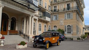 A classic building with a grand entrance, a vintage car parked in front, and a well-maintained garden area. - Cosy studio with a view, central & quiet area (Aix-les-Bains)