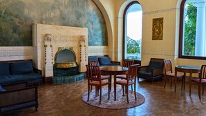 A room with a fireplace, seating, and a view through an arched window. - Cosy studio with a view, central & quiet area (Aix-les-Bains)