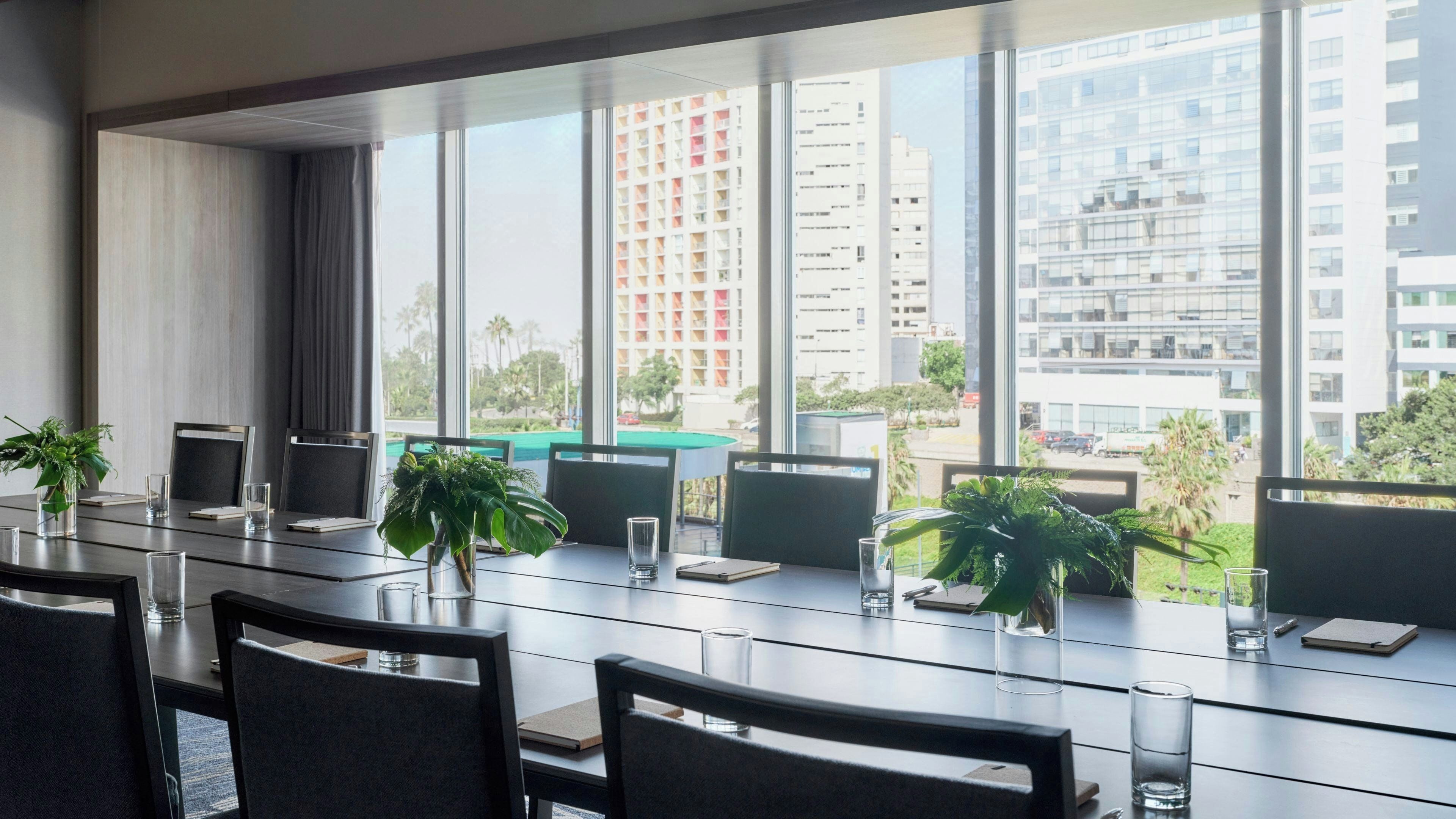 A conference room with a long table, chairs, and potted plants.