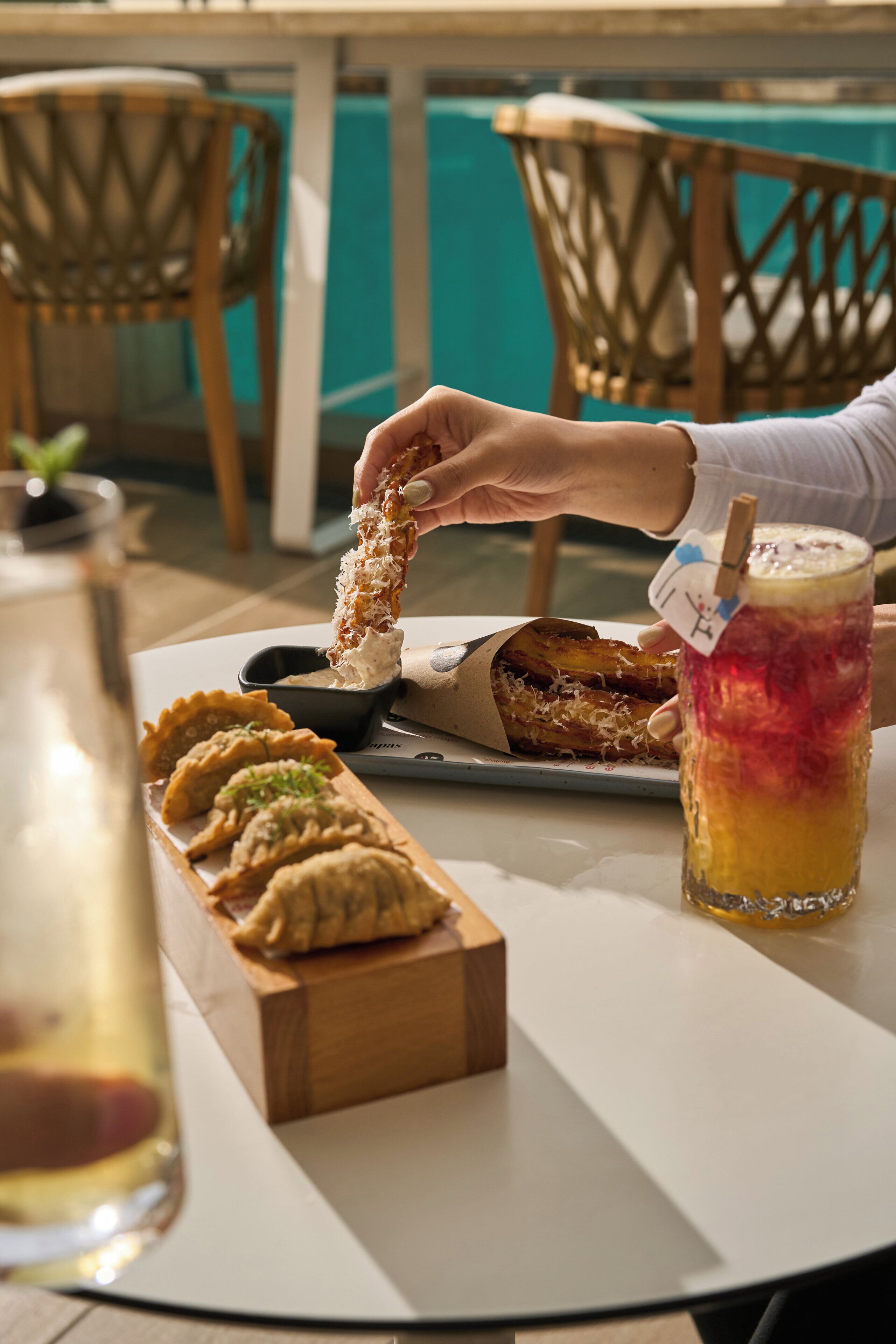 A dining table with a variety of food items, including a tray of pastries and a drink with a straw.