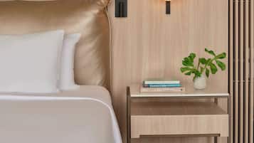 Un dormitorio moderno con cama, mesita de noche, lámpara y una planta en maceta.