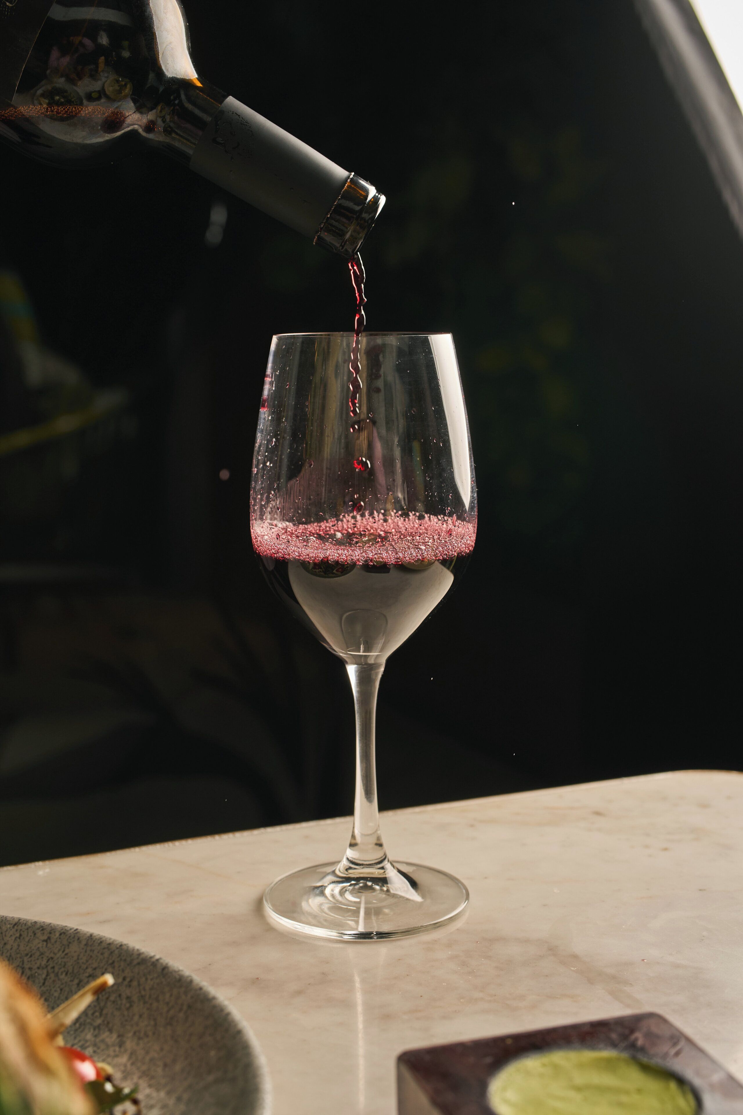 Una copa de vino siendo servida con vino tinto.