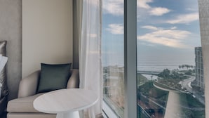 Habitación de hotel moderna con un ventanal que ofrece vistas al océano y a un puente.