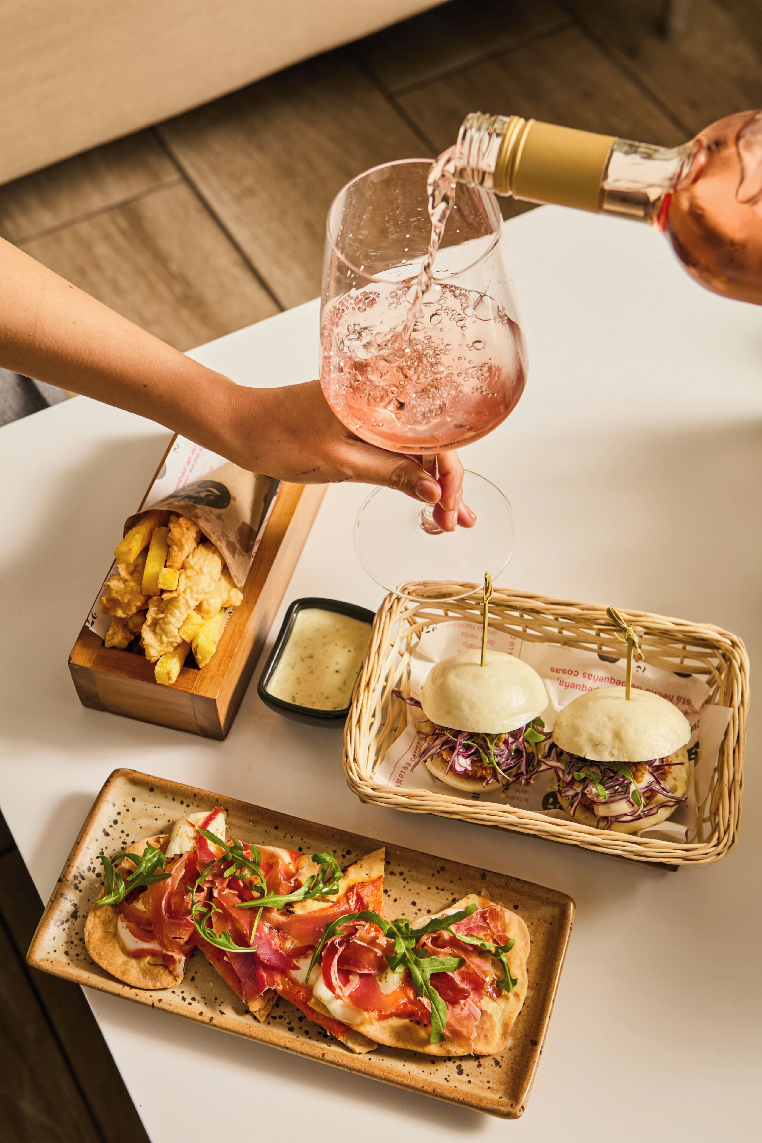 A table with food items and a bottle being poured into a glass.