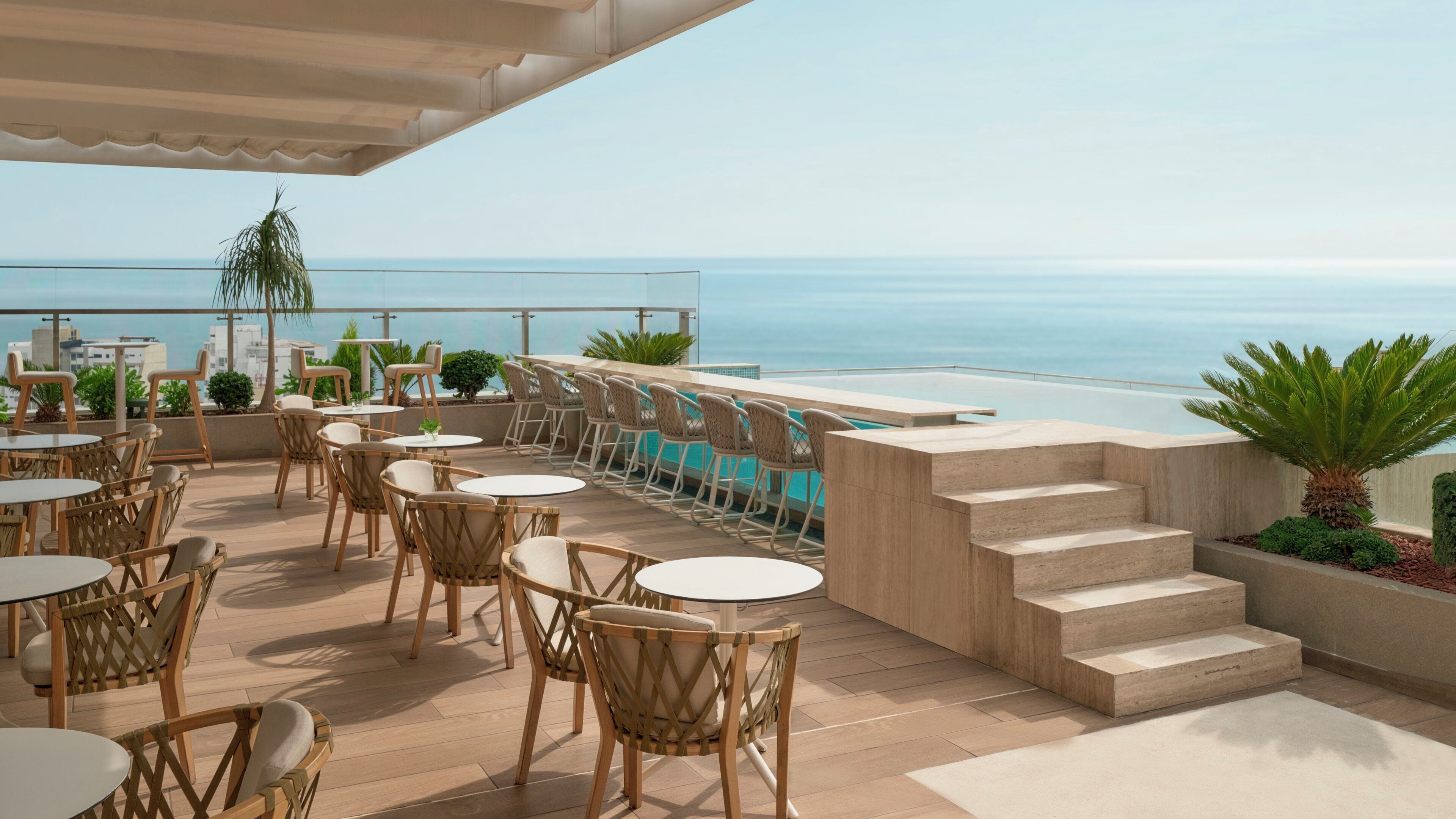A terrace with outdoor seating, a pool, and a view of the sea.