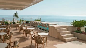 Una terraza con mobiliario exterior, piscina y vistas al mar.
