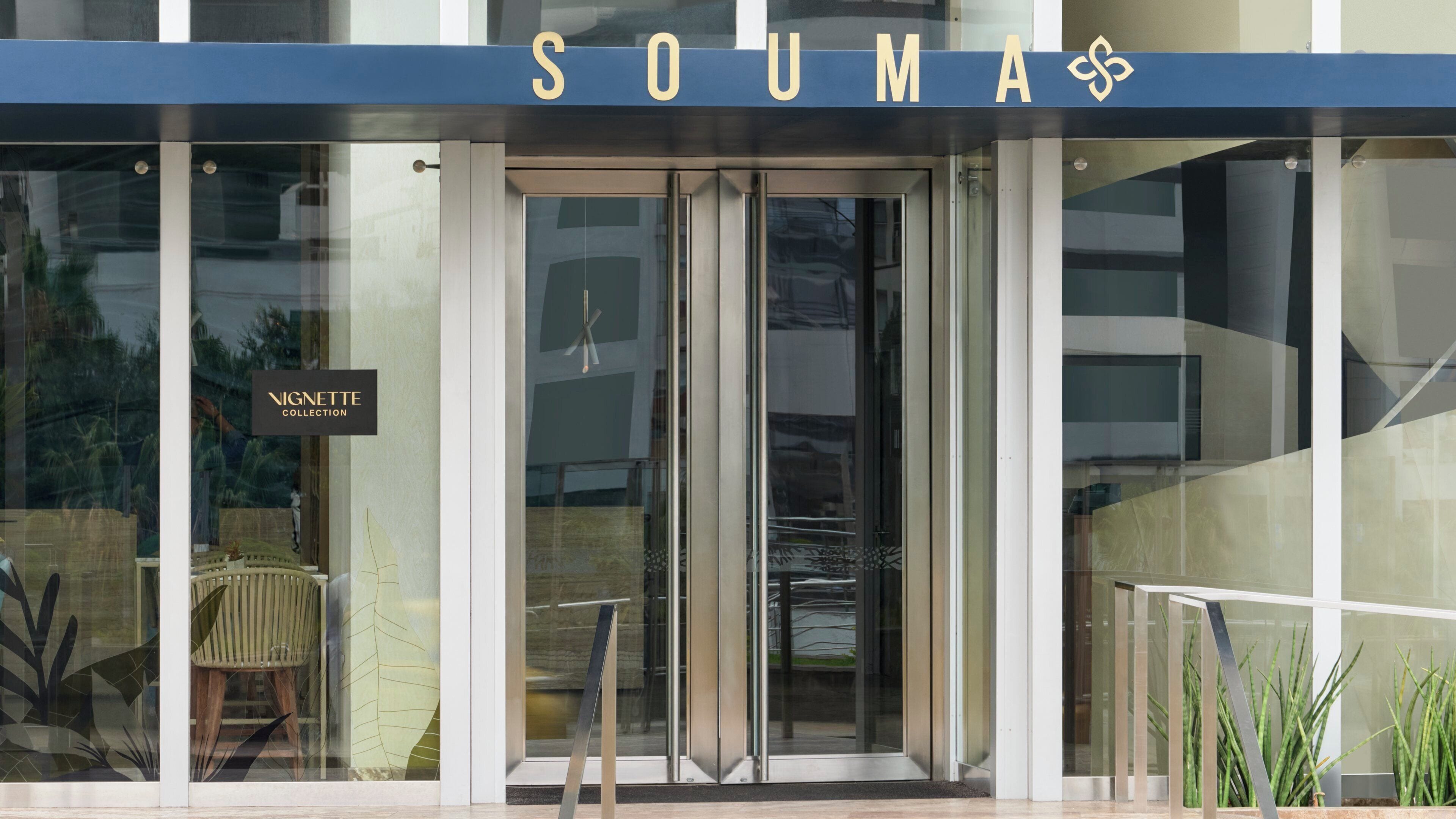 A modern building entrance with a glass door and a sign reading 'SOUMA'.